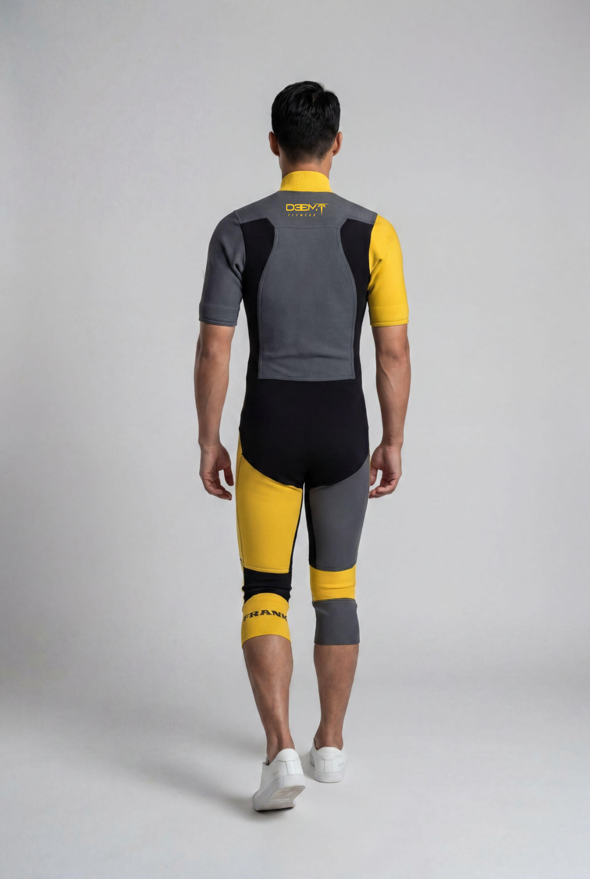 Person wearing a gray and yellow cycling outfit on a plain background